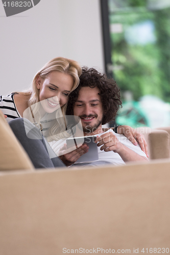 Image of couple relaxing at  home with tablet computers