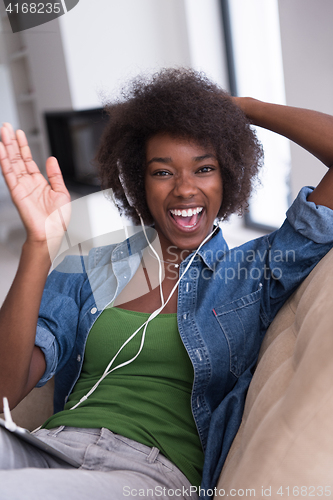 Image of African american woman at home in chair with tablet and head pho