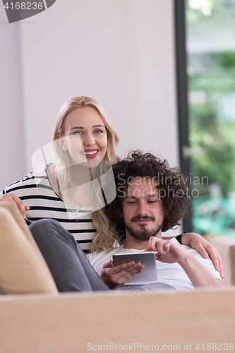 Image of couple relaxing at  home with tablet computers