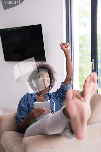 Image of African american woman at home in chair with tablet and head pho