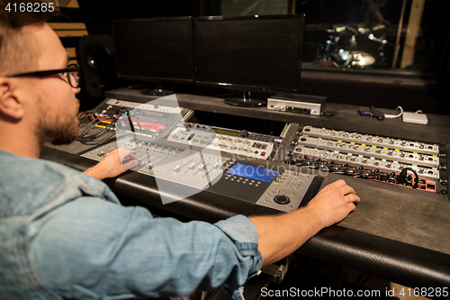 Image of man at mixing console in music recording studio