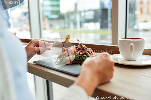 Image of woman eating prosciutto ham salad at restaurant