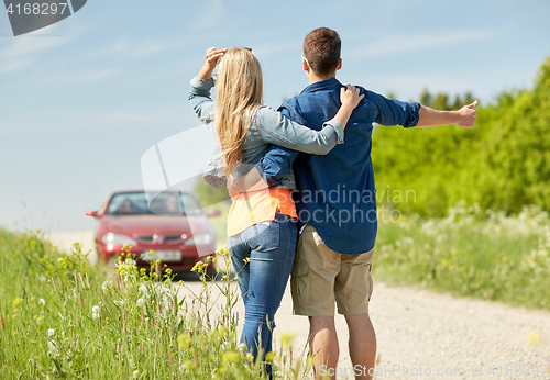 Image of couple hitchhiking and stopping car on countryside