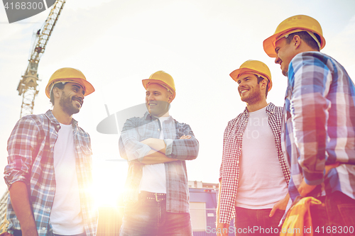 Image of group of smiling builders in hardhats outdoors