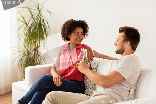 Image of happy friends or couple with beer talking at home