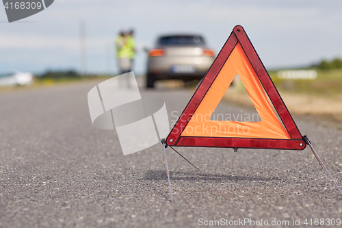 Image of warning triangle over broken car on road