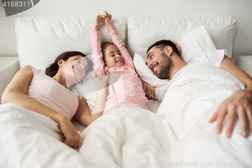 Image of happy family waking up in bed at home