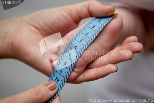 Image of close up of hands with tape measuring baby foot