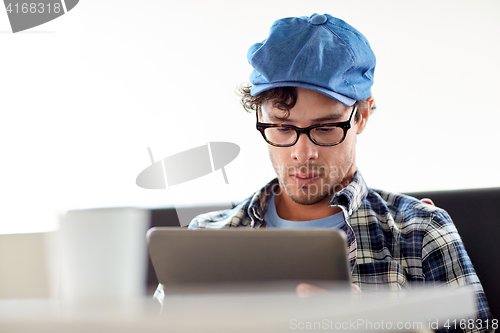 Image of man with tablet pc sitting at cafe table