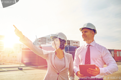 Image of happy builders in hardhats with tablet pc outdoors