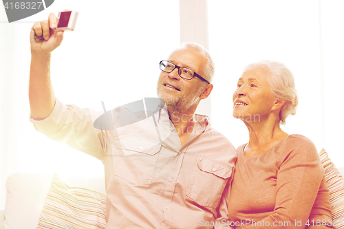 Image of happy senior couple with camera at home