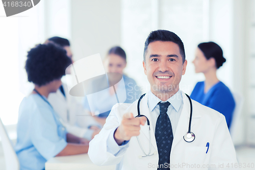 Image of happy doctor over group of medics at hospital