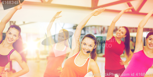 Image of group of smiling people stretching in the gym