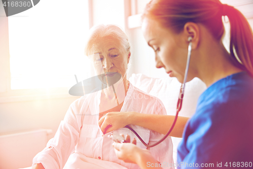 Image of nurse with stethoscope and senior woman at clinic