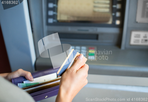 Image of hands with money and credit card at atm machine