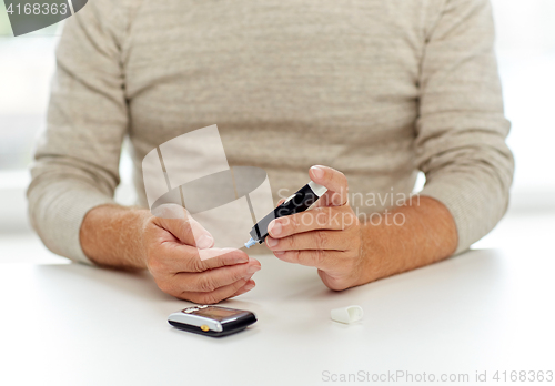 Image of senior man with glucometer checking blood sugar