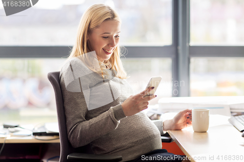 Image of pregnant businesswoman with smartphone at office