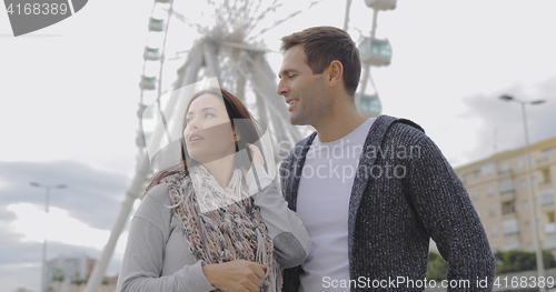 Image of Young couple standing in front of a ferris wheel