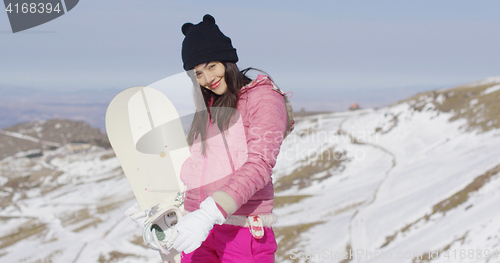 Image of Young woman with snowboard in mountains