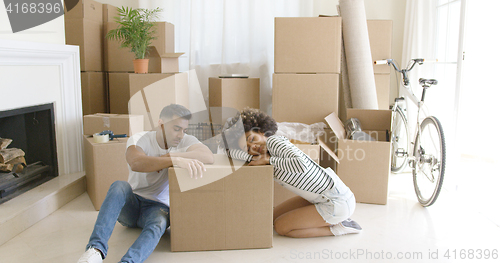 Image of Tired young couple relaxing on cardboard boxes