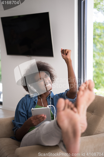 Image of African american woman at home in chair with tablet and head pho