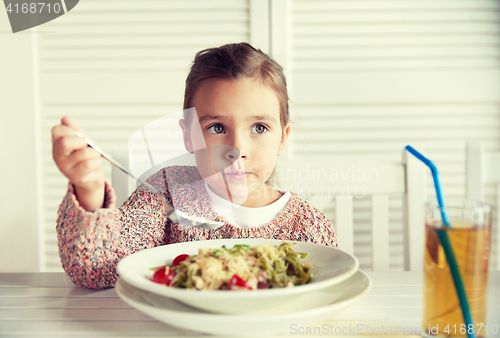 Image of little girl eating pasta for dinner at restaurant