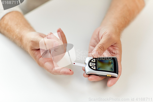 Image of senior man with glucometer checking blood sugar