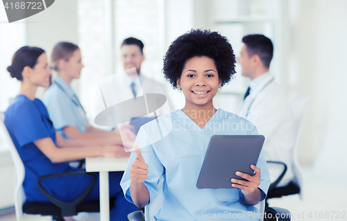 Image of happy doctor with tablet pc over team at clinic