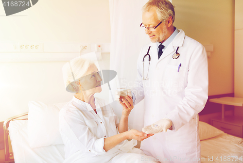 Image of doctor giving medicine to senior woman at hospital