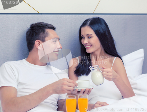 Image of smiling couple having breakfast in bed in hotel