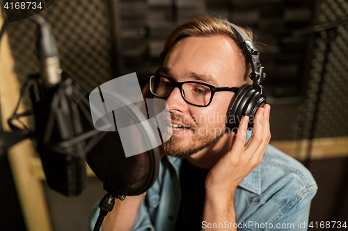 Image of man with headphones singing at recording studio