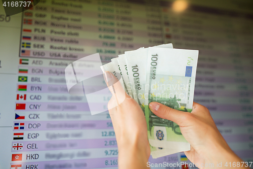 Image of hands with euro money over currency exchange rates