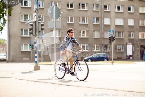 Image of young hipster man with bag riding fixed gear bike