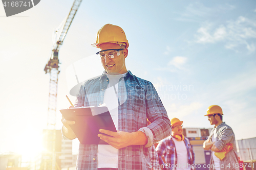 Image of builder in hardhat with clipboard at construction