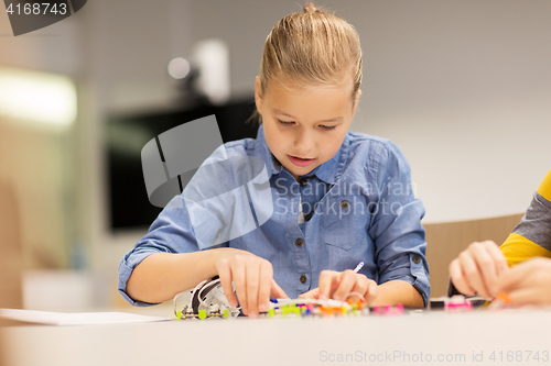 Image of happy girl building robot at robotics school