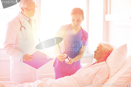 Image of doctor giving medicine to senior woman at hospital