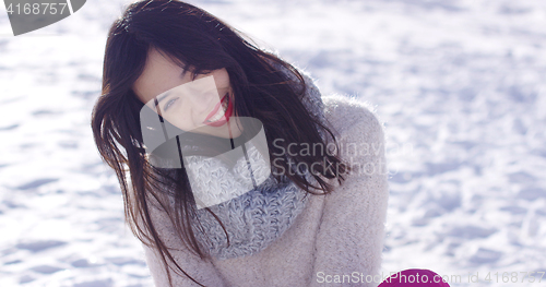 Image of Smiling young woman sat on snow