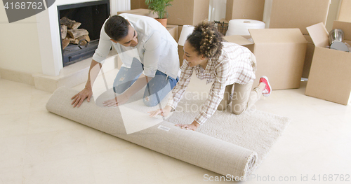 Image of Young couple rolling up a rug as they move house