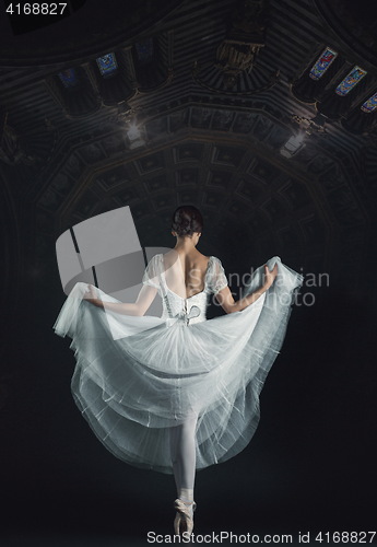 Image of Portrait of the classical ballerina in white dress on black back