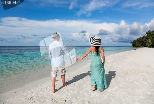 Image of Vacation Couple walking on tropical beach Maldives.