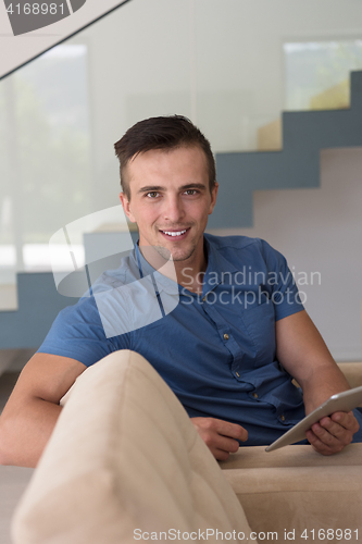 Image of young man using a tablet at home