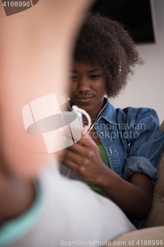 Image of African american woman at home in chair with tablet and head pho