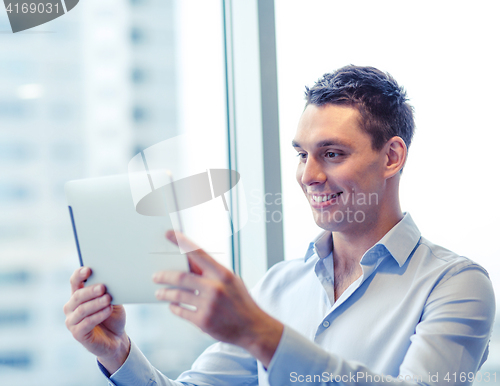 Image of smiling businessman with tablet pc in office