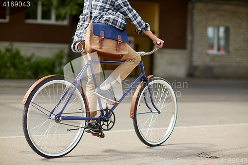 Image of young hipster man with bag riding fixed gear bike