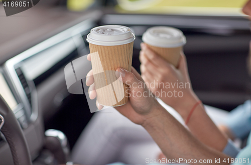 Image of close up of couple driving in car with coffee cups