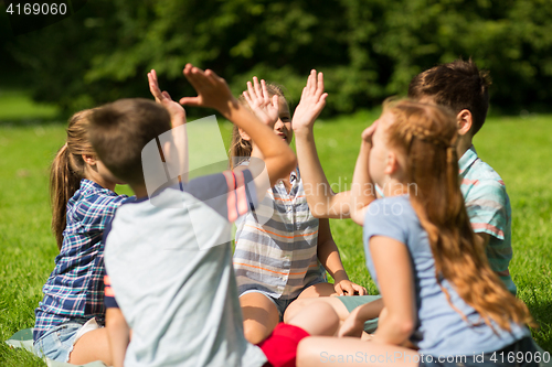 Image of group of happy kids making high five outdoors