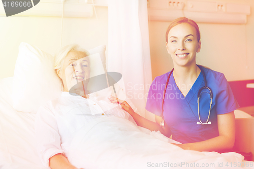 Image of doctor or nurse visiting senior woman at hospital