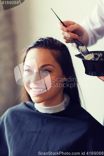 Image of happy woman with stylist coloring hair at salon