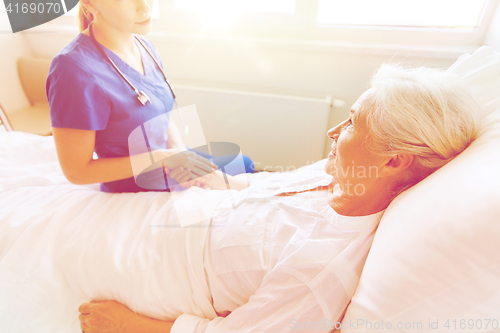 Image of doctor or nurse visiting senior woman at hospital