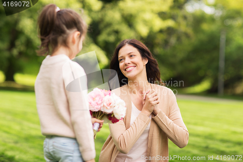 Image of girl giving with flowers to mother in summer park
